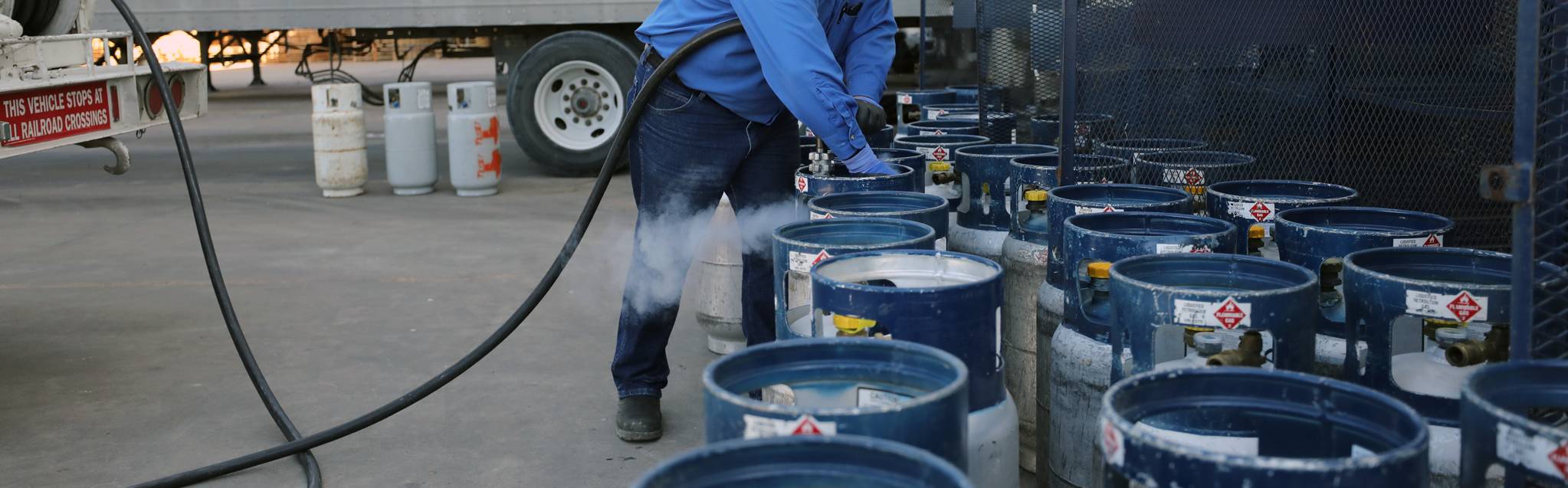 Hino Gas employee refilling propane cylinders from a delivery truck